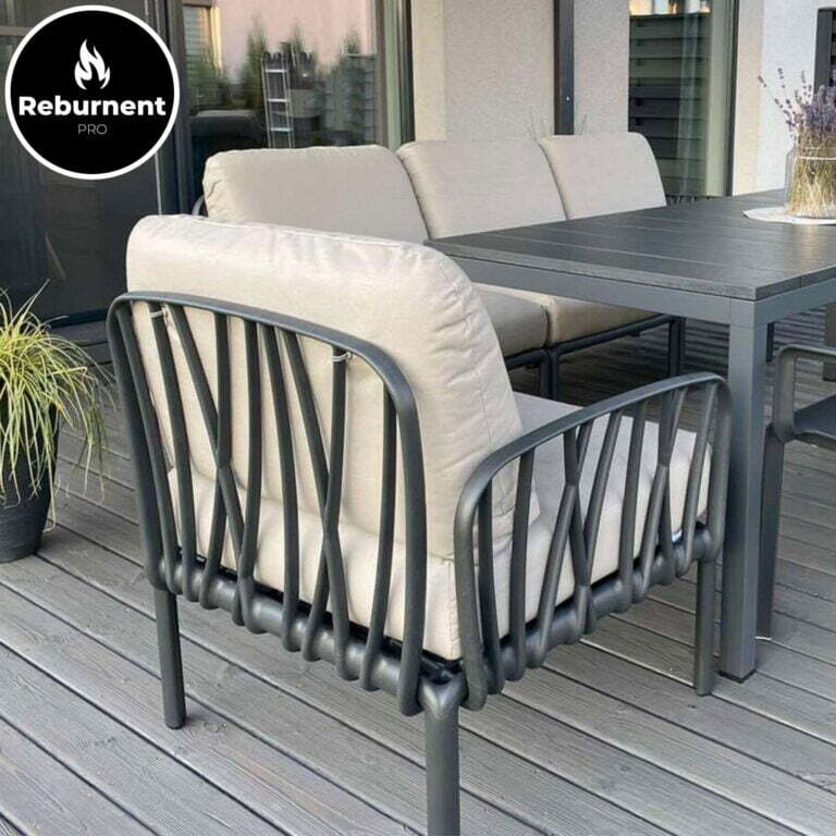 Lauko poilsio baldų komplektas ant degintos medienos dangos su moderniomis metalinėmis kėdėmis ir minkštomis pagalvėlėmis