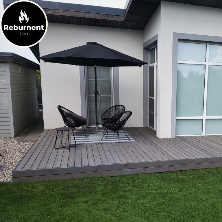 Minimalistinė lauko terasa su šviesaus tono degintos medienos danga ir juodais baldais po skėčiu