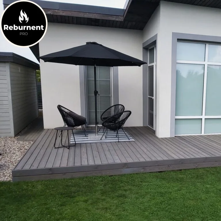 Minimalistinė lauko terasa su šviesaus tono degintos medienos danga ir juodais baldais po skėčiu